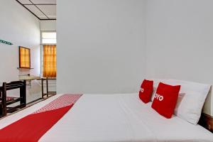 a bedroom with a white bed with red pillows at OYO 92885 Satriafi 2 Hotel in Yogyakarta