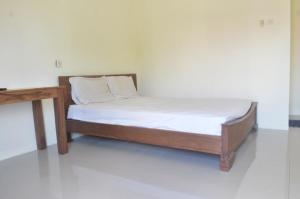 ein Bett mit einem Holzrahmen und einem Holztisch in der Unterkunft OYO 92880 Wisma Nusantara in Manado