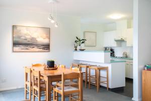 a kitchen and dining room with a wooden table and chairs at Fathoms 9 in Mollymook