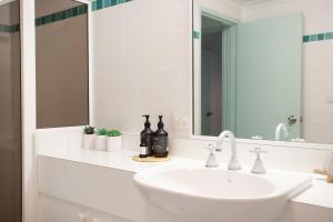 a white bathroom with a sink and a mirror at Fathoms 9 in Mollymook +8 photos
