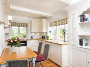 a kitchen with white cabinets and a wooden table at Wattenhof-1 in Kampen