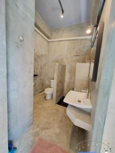 a bathroom with a white sink and a toilet at Baan Suan Plearndara in Wang Nam Khieo