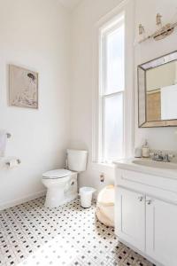 a white bathroom with a toilet and a sink at Luxury Victorian House 10 mins to SF, Rose Garden & 3 Private Parking in Oakland