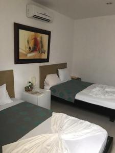 Habitación de hotel con 2 camas y una foto en la pared en Hotel Madrid Deluxe Neiva, en Neiva