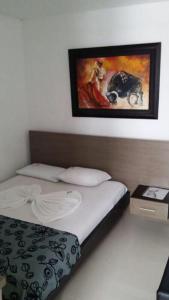 1 dormitorio con 1 cama y una pintura en la pared en Hotel Madrid Deluxe Neiva, en Neiva