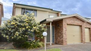 a house with a garage and a tree in front of it at Lighthouse Palms in Ulladulla