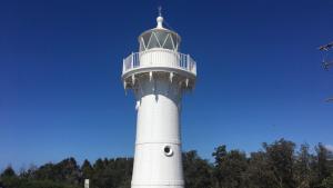 a white lighthouse with a window on the top of it at Lighthouse Palms in Ulladulla +3 photos