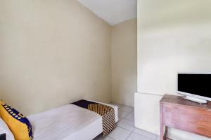 Habitación pequeña con cama y TV de pantalla plana. en SPOT ON 92832 Al Mahira Syariah, en Majalengka
