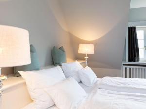 ein Schlafzimmer mit einem weißen Bett mit weißen Kissen in der Unterkunft Prahl Hüs 3 in Kampen