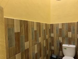 baño con aseo y azulejos de madera en la pared en OYO 92899 Penginapan Laota Syariah, en Luwuk