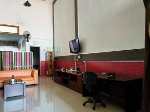 ein Wohnzimmer mit einem Schreibtisch und einem TV an der Wand in der Unterkunft SPOT ON 92900 Kost 3 Kelor Syariah in Luwuk