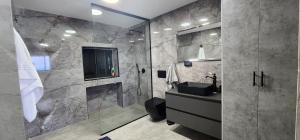 uma casa de banho com um chuveiro, um lavatório e um WC. em מבנים בים 77 Suites at sea em Haifa