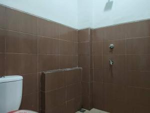 ein Badezimmer mit einer braun gefliesten Dusche und einem WC in der Unterkunft SPOT ON 92900 Kost 3 Kelor Syariah in Luwuk
