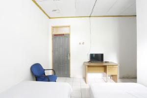 a room with a blue chair and a desk and a door at OYO 92865 Guest House Pandita in Sebawang