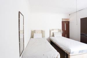- 2 lits dans une chambre avec un miroir dans l'établissement OYO 92865 Guest House Pandita, à Sebawang