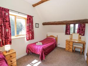 a bedroom with a bed and a desk and a window at Betty's Barn in Eaton