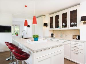 una cocina con armarios blancos y taburetes rojos en Landhaus-Mare, en Kampen