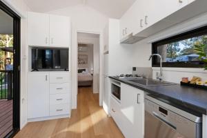 a kitchen with white cabinets and a sink at Reflections Moonee Beach - Holiday Park in Moonee Beach