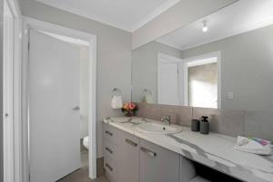 een witte badkamer met een wastafel en een spiegel bij TheRiverbend43 Wellington Marina in Wellington East