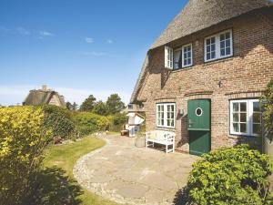 ein Backsteinhaus mit einer grünen Tür und einer Terrasse in der Unterkunft Hortensienhüs West in Kampen