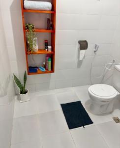 a white bathroom with a toilet and a shelf at Sally's home-near JNIA airport in Dar es Salaam