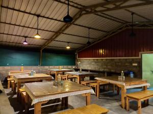 an empty restaurant with wooden tables and chairs at LABDHI RESORTS Stag Groups not allowed in Masinagudi