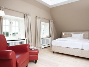 - une chambre avec un lit et une chaise rouge dans l'établissement Haus-zum-Leuchtturm, à Kampen