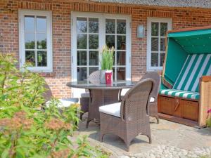 eine Terrasse mit einem Tisch, Stühlen und einem Grill in der Unterkunft Prahl Hüs 3 in Kampen