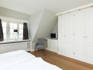 a bedroom with a bed and a desk and a tv at Prahl-Hues-3 in Kampen