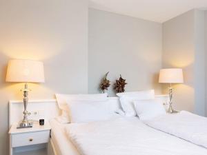 a bedroom with two beds with white sheets and lamps at Prahl-Hues-5 in Kampen