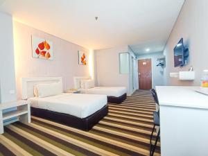 een hotelkamer met 2 bedden en een bureau bij First Residence Hotel by RVH in Cukai