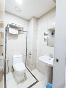 een witte badkamer met een toilet en een wastafel bij First Residence Hotel by RVH in Cukai