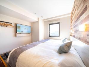 a large bed in a bedroom with two windows at Super Hotel Premier Shimonoseki in Shimonoseki