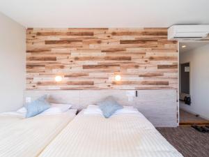 a bedroom with two beds and a wooden wall at Super Hotel Premier Shimonoseki in Shimonoseki