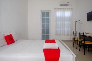 a bedroom with a large white bed with red pillows at RedDoorz at Golden White House Pettarani in Makassar