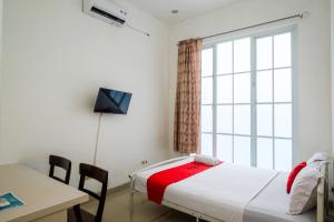 Schlafzimmer mit einem Bett, einem Schreibtisch und einem Fenster in der Unterkunft RedDoorz at Golden White House Pettarani in Makassar
