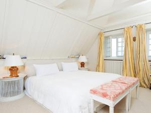 a white bedroom with a white bed and two lamps at Pueckdeel in Kampen