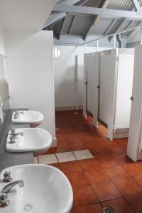 a bathroom with three sinks and stalls at YHA Alice Springs in Alice Springs