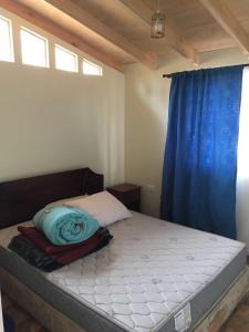 1 cama en un dormitorio con cortina azul en Cabañas Ocean Forest, en El Tabo