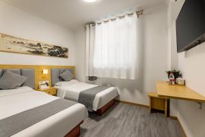a hotel room with two beds and a television at Happy Dragon Hotel National Art Museum Metro Forbidden City in Beijing