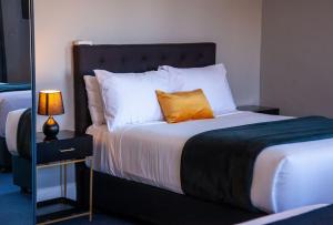 a bedroom with a bed with a orange pillow on it at Bayswater Boutique Lodge in Sydney