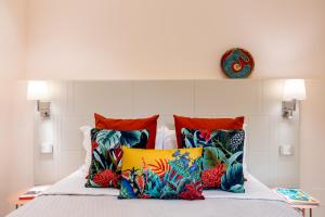 a bed with four colorful pillows on it at Magnini Rooms in Cagliari