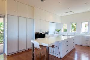 ダンズボローにあるBilyarra I Private Propertiesの白いキャビネットとスツール付きの大きな島のあるキッチンが備わります。 +18枚の写真