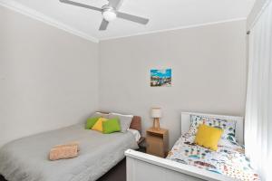 Un dormitorio con una cama y un ventilador de techo. en Pacifica, en Mollymook