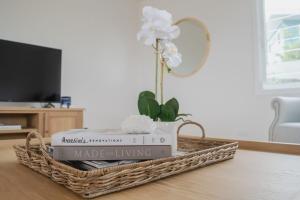a basket with books and a flower on a table at Palm Tree Retreat in Mollymook