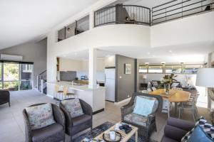 a living room with a table and chairs and a kitchen at Surfers Reef Escape Mollymook in Mollymook