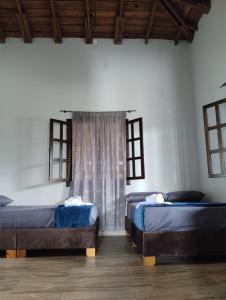 two beds in a room with two windows at Encanto cafetero quimbaya in Quimbaya