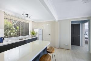 a white kitchen with a sink and a counter at Rennies Sands in Ulladulla