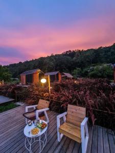 a deck with two chairs and a table with a plate of food at The Maewin Coffee & Cottage Economy Double Room in Ban Huai Rin +12 photos