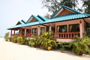a house with a blue roof on the beach at Nice Sea Resort in Srithanu